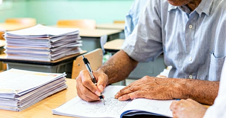 Teacher's hands writing in students' notebooks