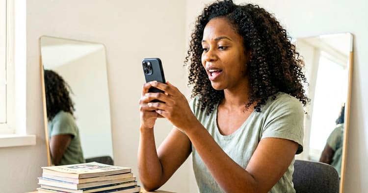 Young Mozambican woman studying English for a job interview using a mobile phone and notebook