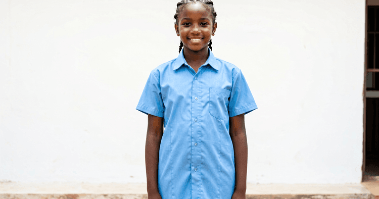 15 to 17-year-old Mozambican teenage girl in a courtyard smiling starting her first job