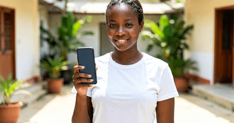 Young Mozambican woman in a bank branch courtyard with a mobile phone