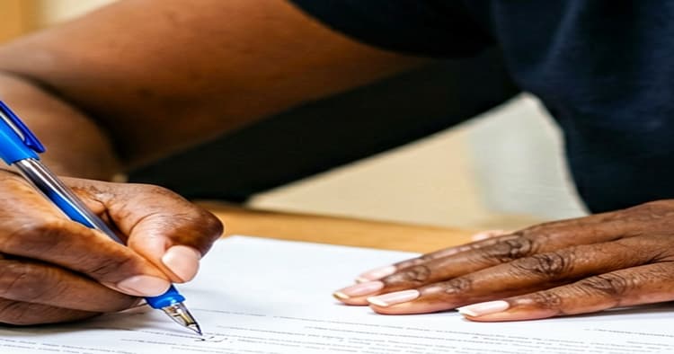 Young Mozambican man signing an internship contract at an office desk