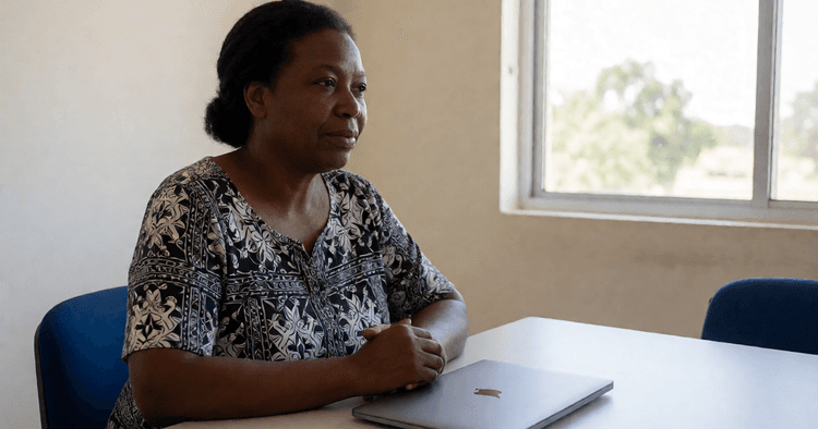 Profissional moçambicana em escritório de ONG, mesa limpa e portátil fechado