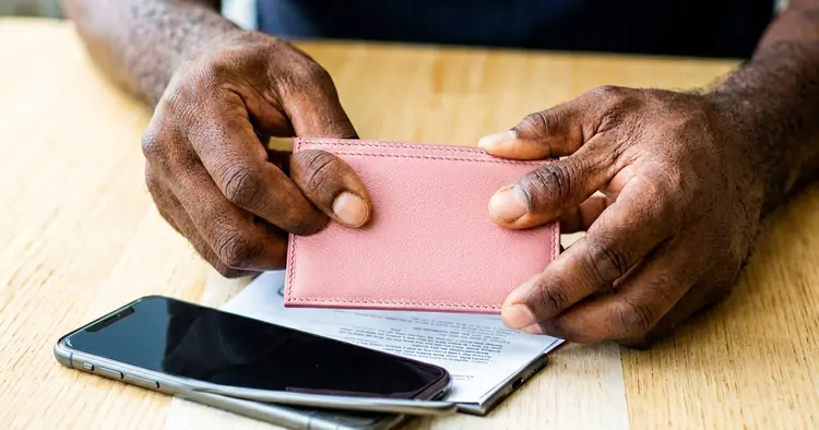 Hands holding a driver's license and a mobile phone on the table
