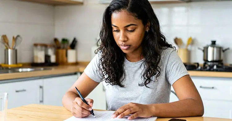 Young person calculating net salary in a notebook with a pen