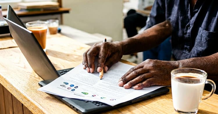 Hands reviewing a PDF document on a laptop before sending an application