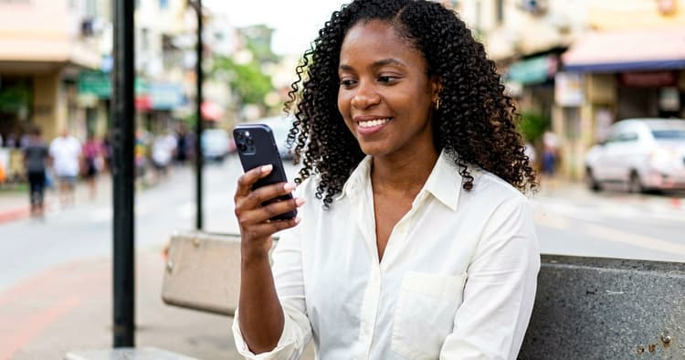 Mozambican female professional managing her LinkedIn profile on her mobile phone at a terrace café