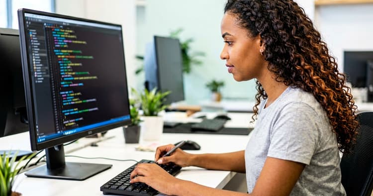 Mozambican female developer writing code on a laptop in a modern workspace
