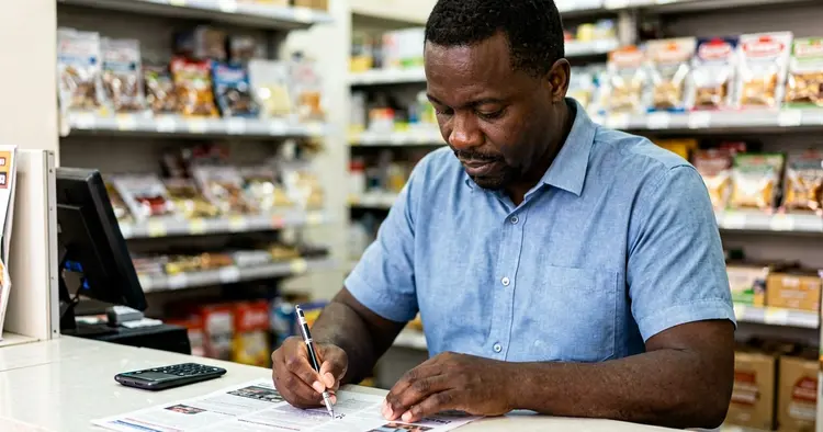 small business owner writing job ad on laptop at shop counter