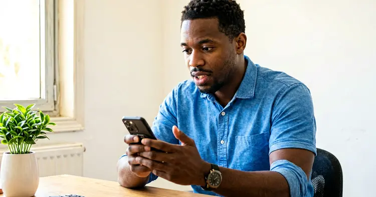 Jovem moçambicano a preencher um modelo de CV simples em Word no telemóvel, em casa