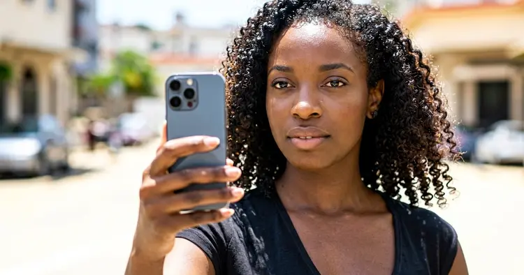 Mozambican candidate preparing her job application on her mobile phone, urban street