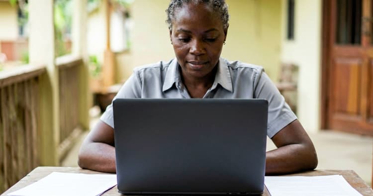 Female applicant sending CV by email to European employer, screen seen from behind
