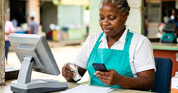 trabalhadora a fazer conciliação de caixa com M-Pesa e POS
