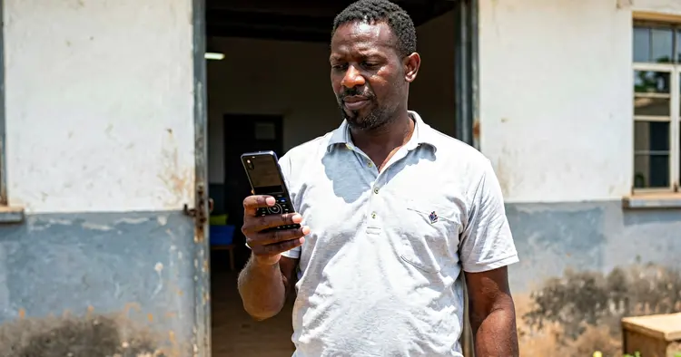 Mozambican worker checking overtime hours on a payslip on a mobile phone