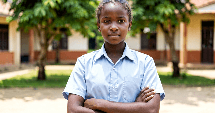Young Mozambican woman in a school courtyard with crossed arms preparing for employability programs