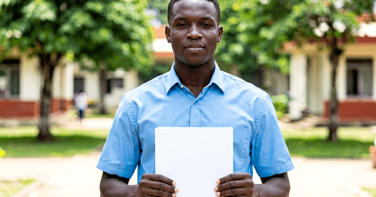 Young Mozambican in a technical school yard holding a certificate