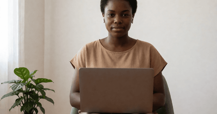 Mozambican female worker with headphones in a quiet home office, laptop facing away from the camera