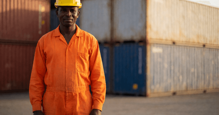 Mozambican dockworker standing next to shipping containers at the end of the day